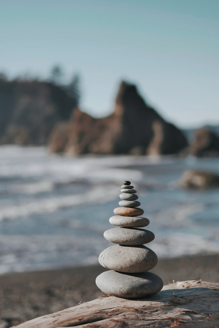 Serene beach scene with stacked stones symbolizing harmony and stability against ocean backdrop.