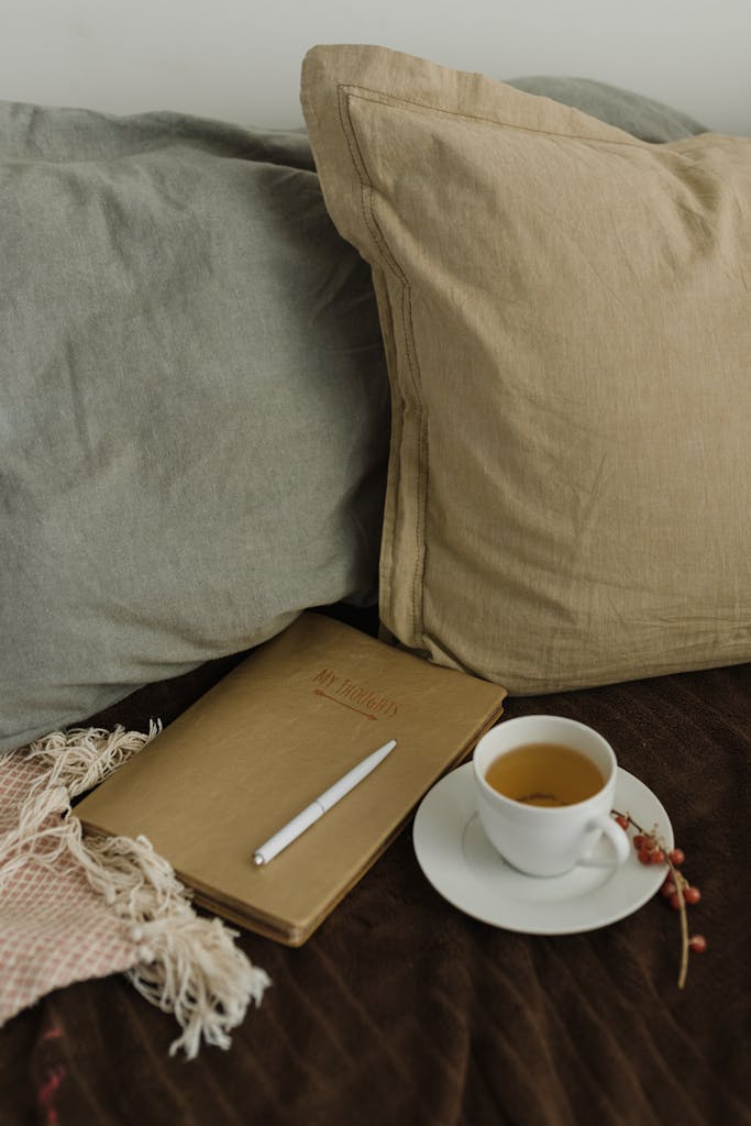 Warm and inviting setting with tea, notebook, and throw pillows, perfect for relaxation.